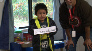 Native American Kid Holding Up Ojibwe Word with Teacher