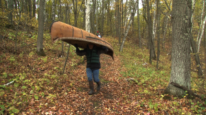 Man Carrying Birchbark Canoe in Woods